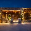 Beautiful Lithos Cave Villa with outdoor lighting in Agrari, Mykonos, at dusk.