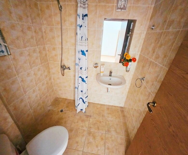 Bathroom with shower, sink, and mirror in Sunny Beach apartment.