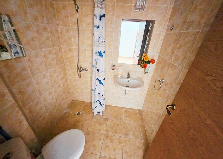 Bathroom with shower, sink, and mirror in Sunny Beach apartment.