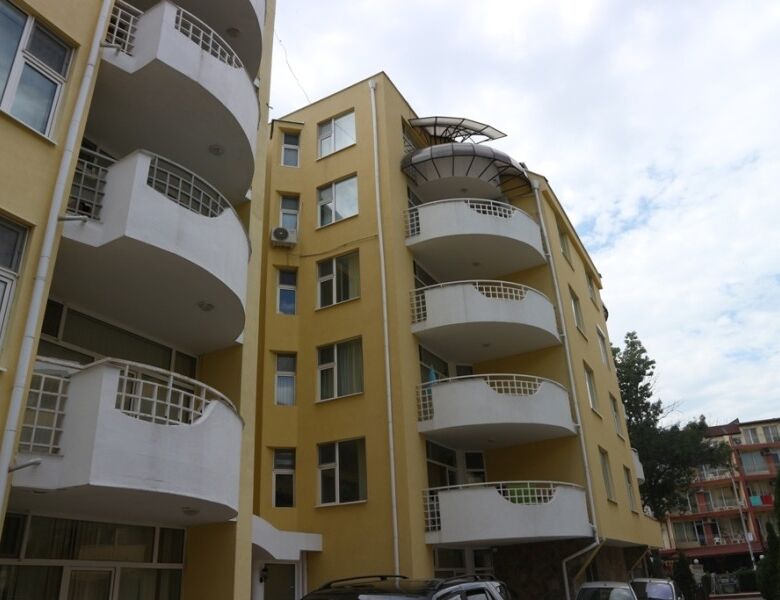 Modern yellow apartment building with curved balconies in Sunny Beach.