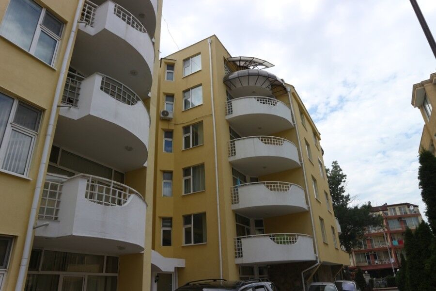 Modern yellow apartment building with curved balconies in Sunny Beach.