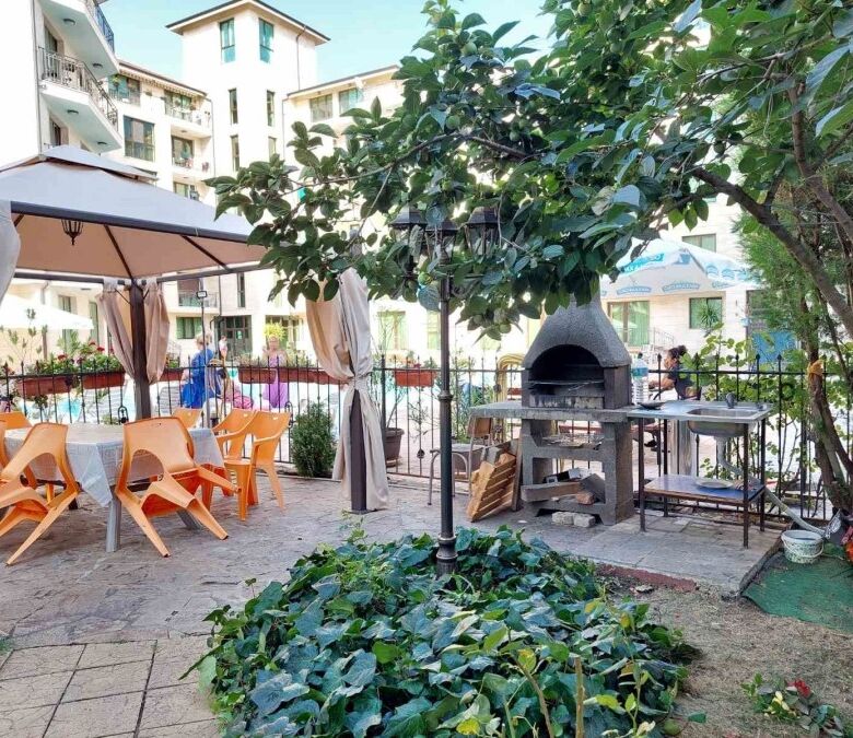 Outdoor dining space with tables, chairs, and a barbecue grill in Amber Beach, Sunny Beach resort.