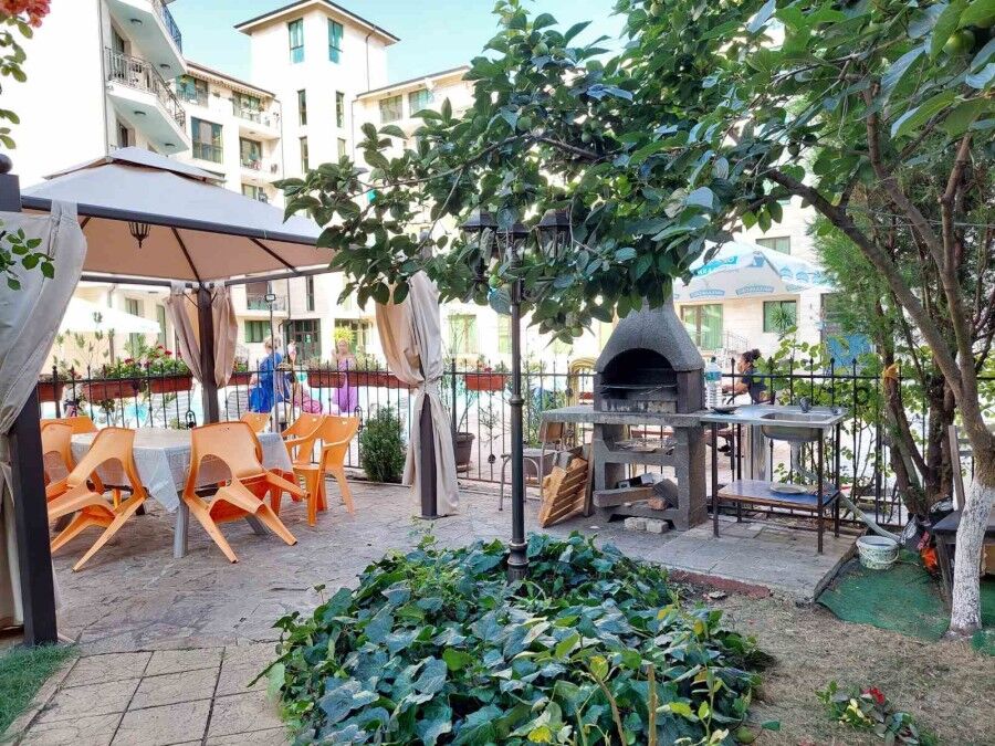 Cozy outdoor dining area in Amber Beach resort Outdoor dining space with tables, chairs, and a barbecue grill in Amber Beach, Sunny Beach resort.