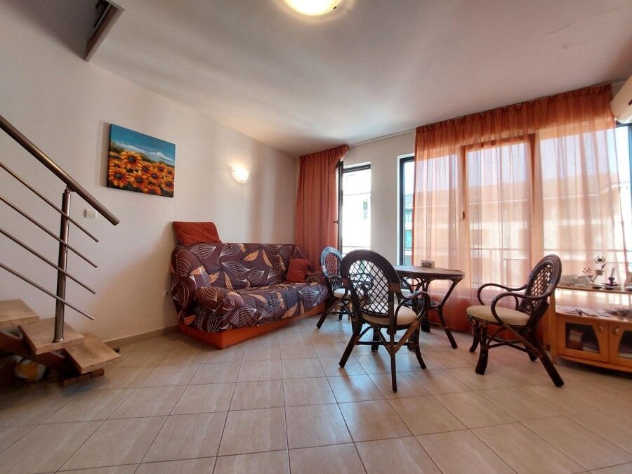 Maisonette for sale in Amber Beach, Sunny Beach resort Bright living room with sofa, dining table, and large windows.