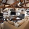 Cozy living room with rustic wooden beams and stone accents in a luxury penthouse in Agordo Dolomite.