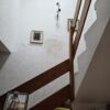 Interior view of a townhouse staircase with wooden handrails and white walls.