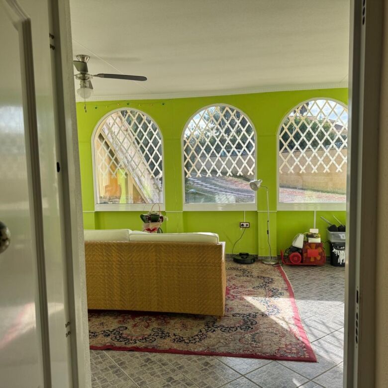 Spacious living room with large arched windows and vibrant green walls. Perfect family home in a pea.