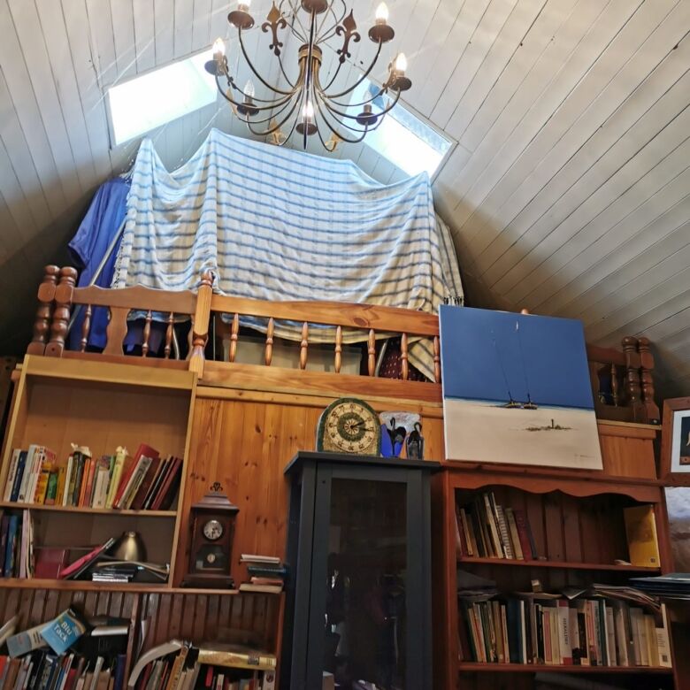 Cozy interior of a Sligo home featuring a loft area with bookshelves and a chandelier.