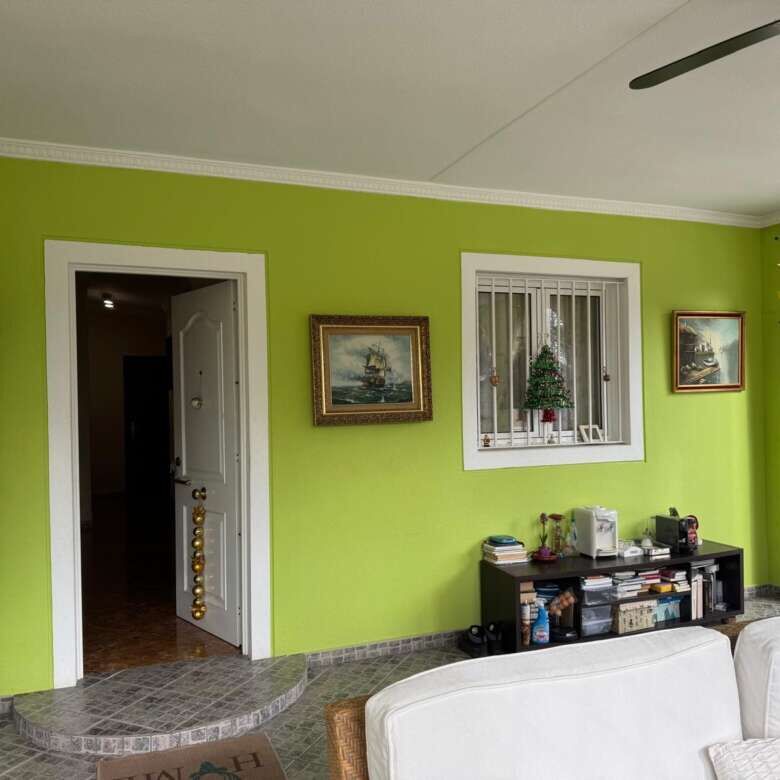 Bright living room with green walls, white furniture, and large windows in a villa for sale in El Ca.