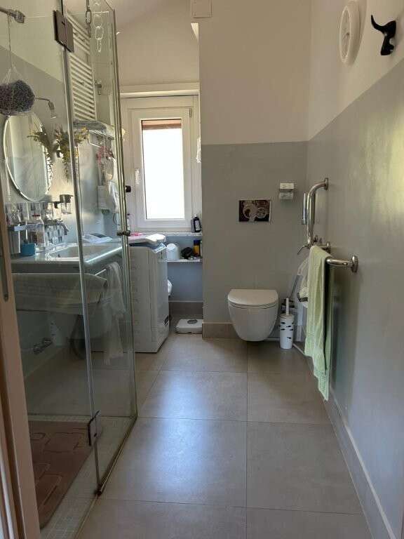 Modern bathroom with toilet, towel rail, and window in Ariccia Rome penthouse.