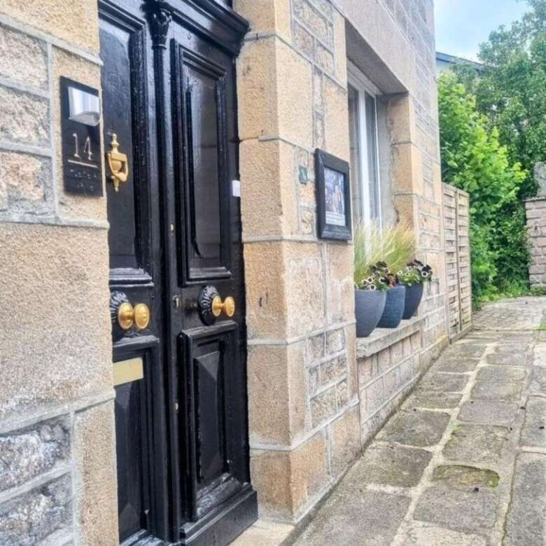 Elegant stone mansion entrance with black door and decorative details in Bugeat.