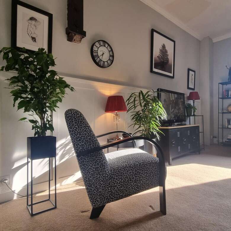 Bright living room featuring contemporary furniture, artwork, and large windows allowing ample sunli.