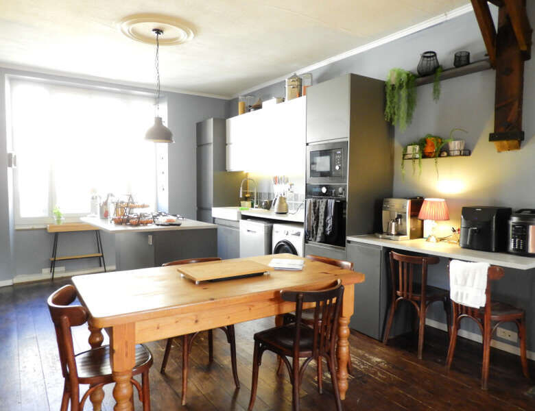 Cozy kitchen with rustic wooden dining table and modern appliances in a historic stone mansion. Brig.