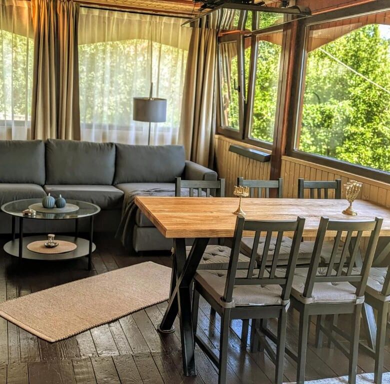 Bright living room with large windows overlooking lush greenery, featuring a comfortable sofa and a.
