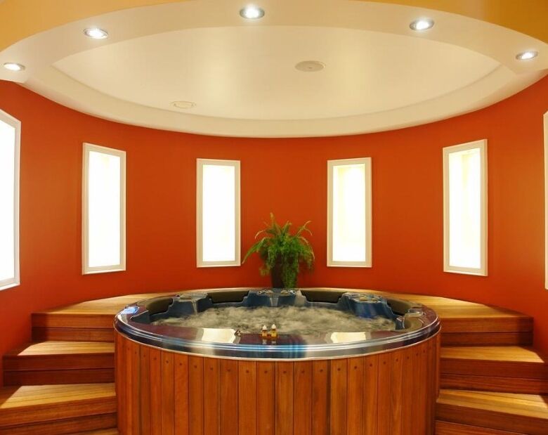 Indoor Jacuzzi with multiple windows and warm lighting.