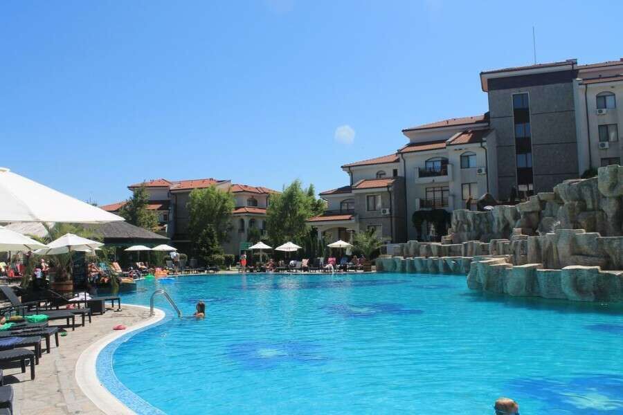 Pool view of Vineyards SPA Resort apartment complex with outdoor swimming pool and sun loungers.