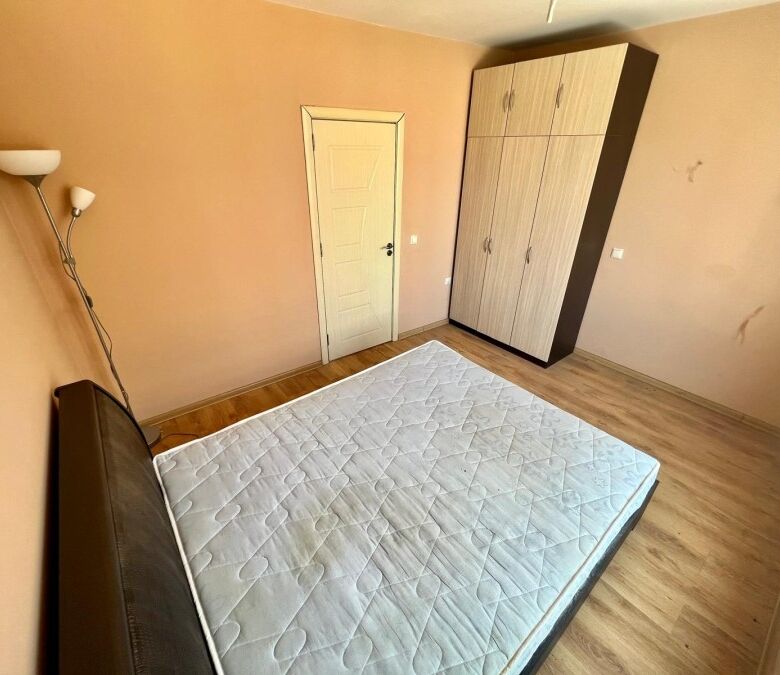 Interior view of a 1-bedroom apartment in Ravda, featuring a bed, wardrobe, and simple decor.