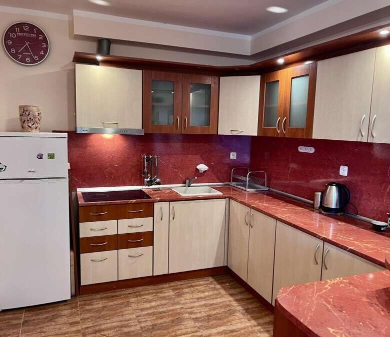 Modern kitchen with red countertops and wooden cabinets in a spacious studio apartment.