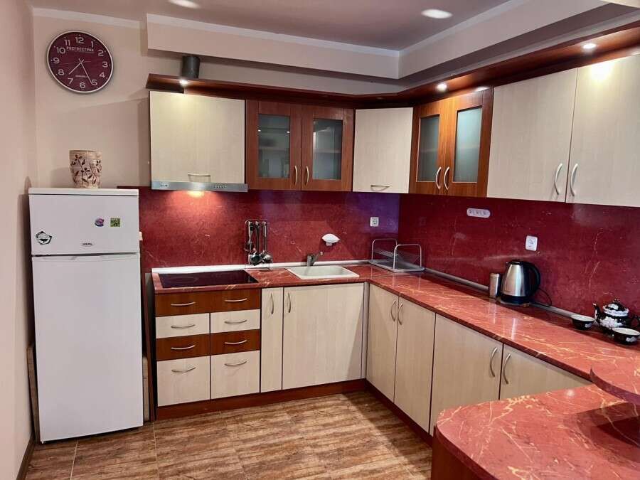 Modern kitchen with red countertops and wooden cabinets in a spacious studio apartment.