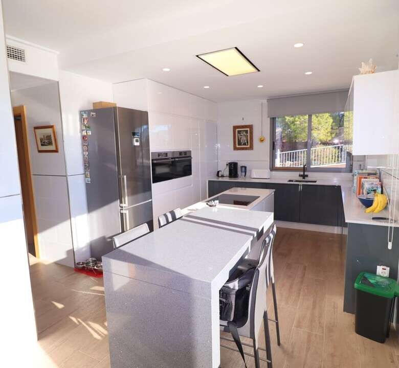 Spacious kitchen featuring white cabinetry, stainless steel appliances, and a large island in a luxu.
