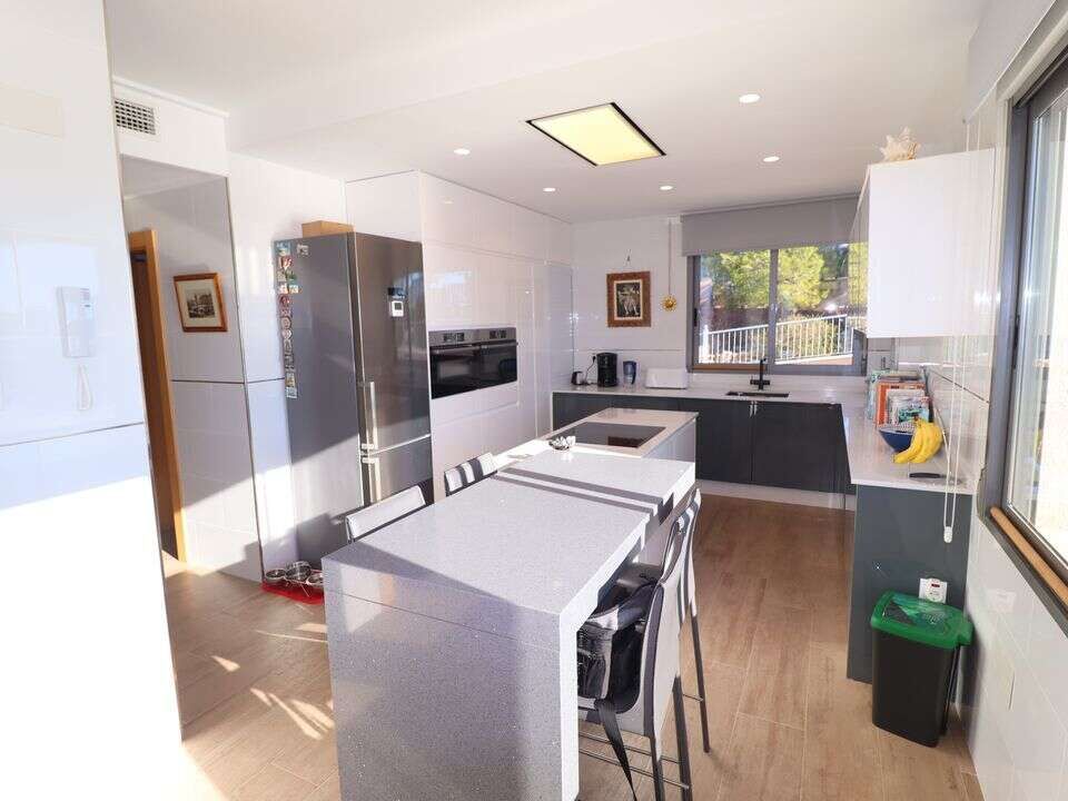 Spacious kitchen featuring white cabinetry, stainless steel appliances, and a large island in a luxu.