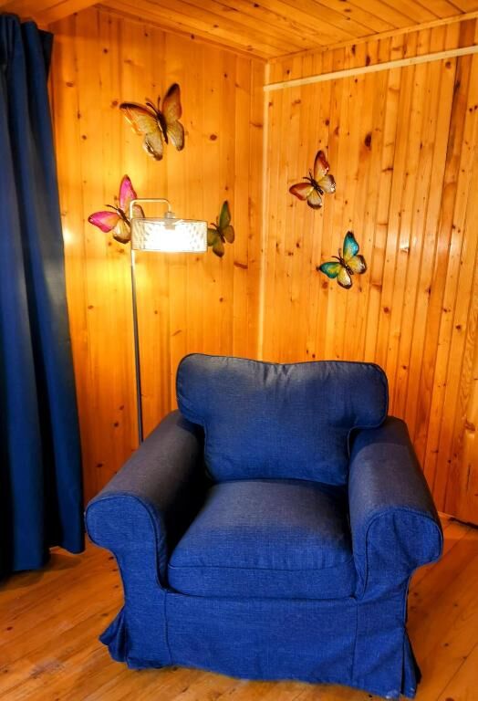 Comfortable blue armchair in a warm wooden interior with butterfly wall decor.