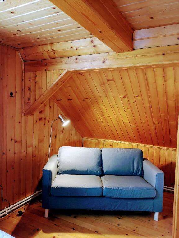 Cozy wooden attic living space with a modern sofa in Chiriteni. Perfect for relaxing in a charming,.