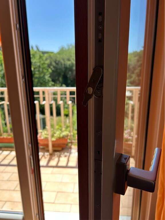 Balcony door in a penthouse apartment offering scenic views of lush greenery and outdoor space.