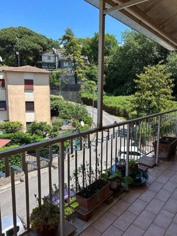 Balcony view from a luxurious 2-bed penthouse in Ariccia, Rome, showcasing lush greenery and citysca.