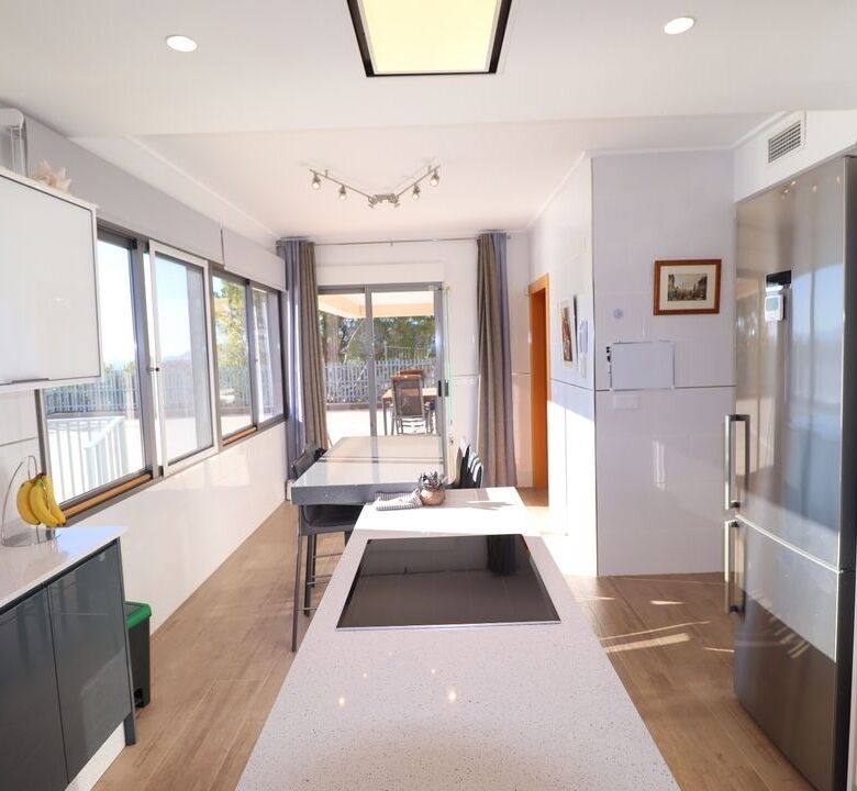 Spacious modern kitchen with large windows, white cabinets, and sleek appliances in a luxury villa i.