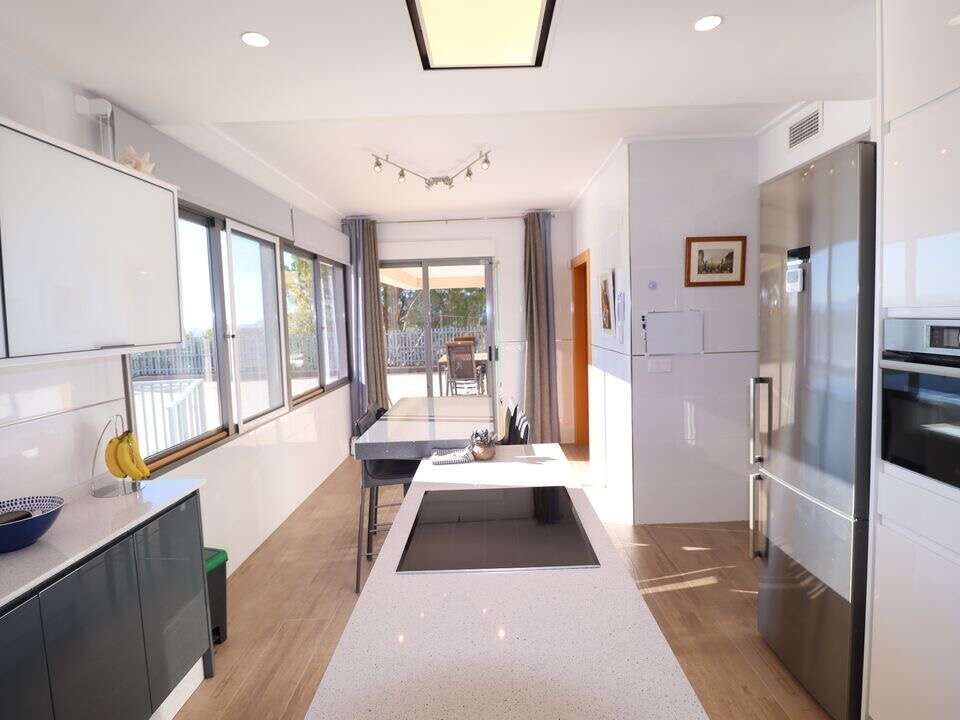 Spacious modern kitchen with large windows, white cabinets, and sleek appliances in a luxury villa i.