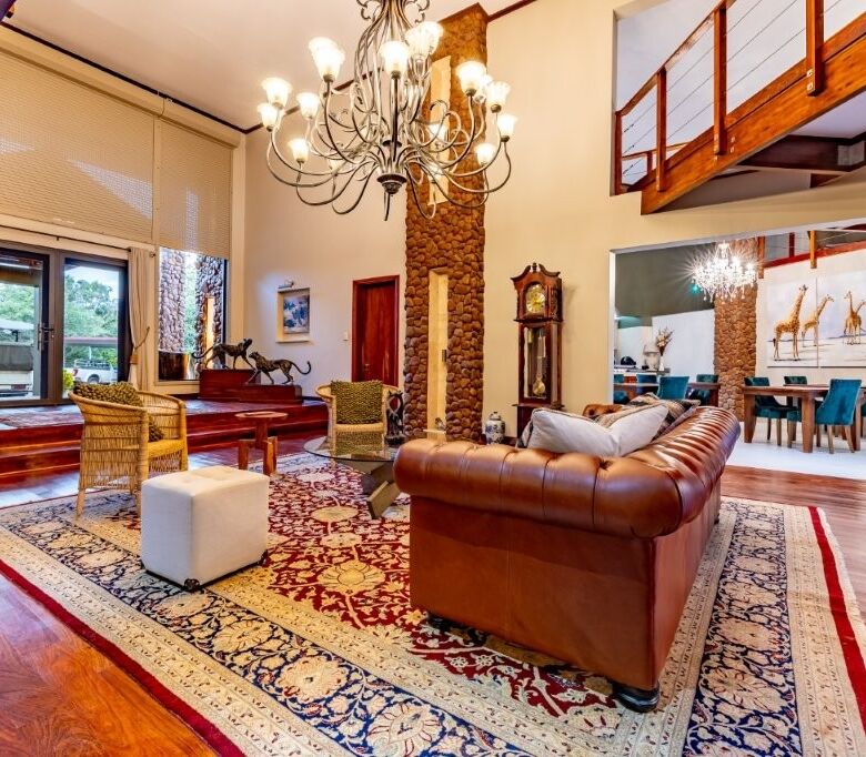 Spacious living room with high ceilings, elegant decor, and large windows overlooking lush surroundi.