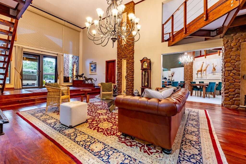 Spacious living room with high ceilings, elegant decor, and large windows overlooking lush surroundi.