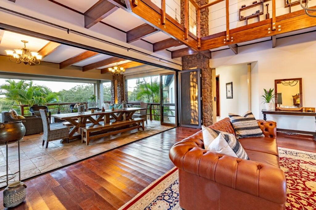 Elegant living room with large glass doors opening to lush outdoor scenery in Hluhluwe Kwa-Zulu Nata.