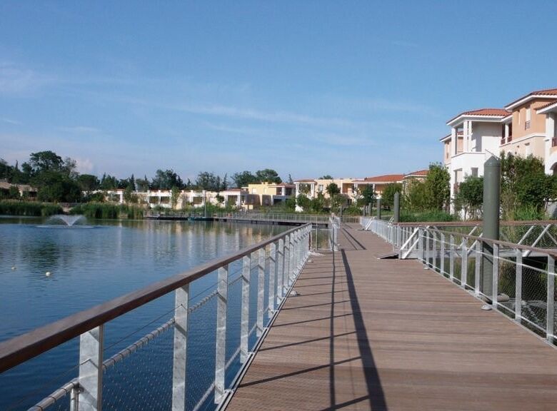 Scenic view of a lakeside walkway in Mandelieu La Napoule, Cannes, with residential buildings in the.