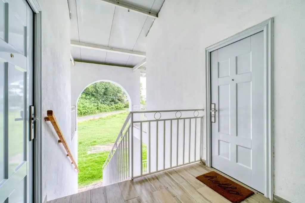 Bright condo entrance with white walls and wooden flooring in Pedasi.
