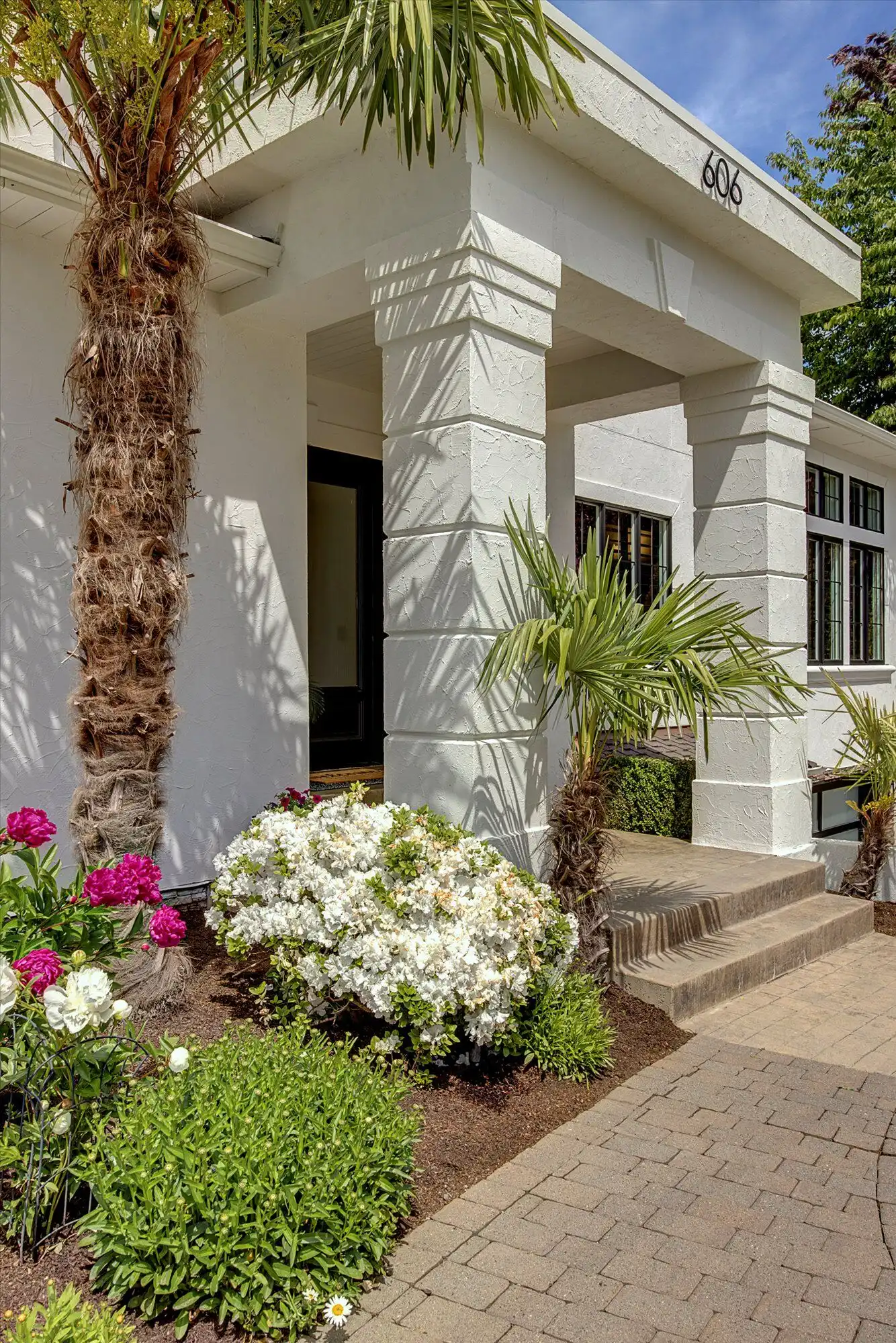 Modern luxury home with tropical landscaping and palm trees by the lake.
