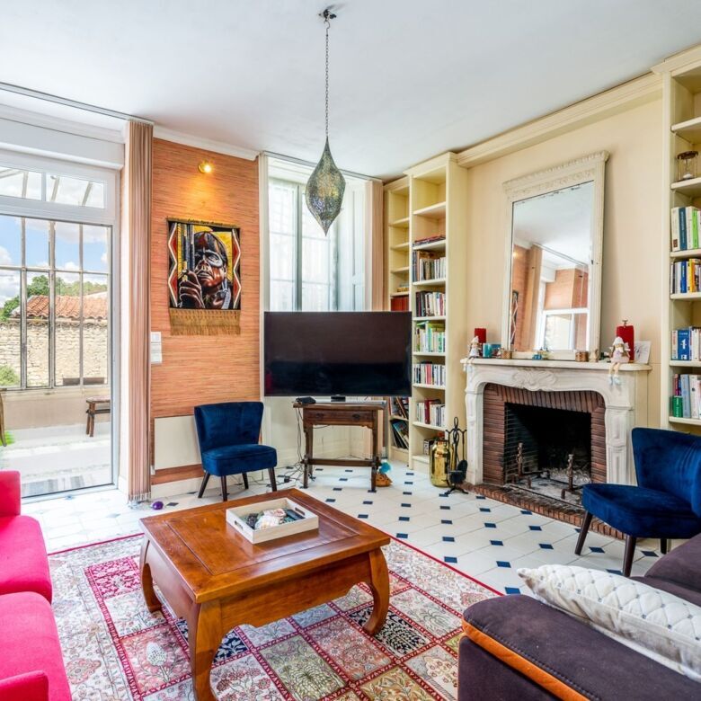 Spacious living room with fireplace, bookshelves, and large windows in this beautiful 7-bedroom hous.