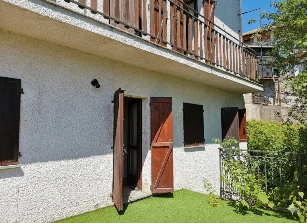 Beautiful exterior view of a two-bedroom villa with wooden shutters and a small garden in Piedmont.