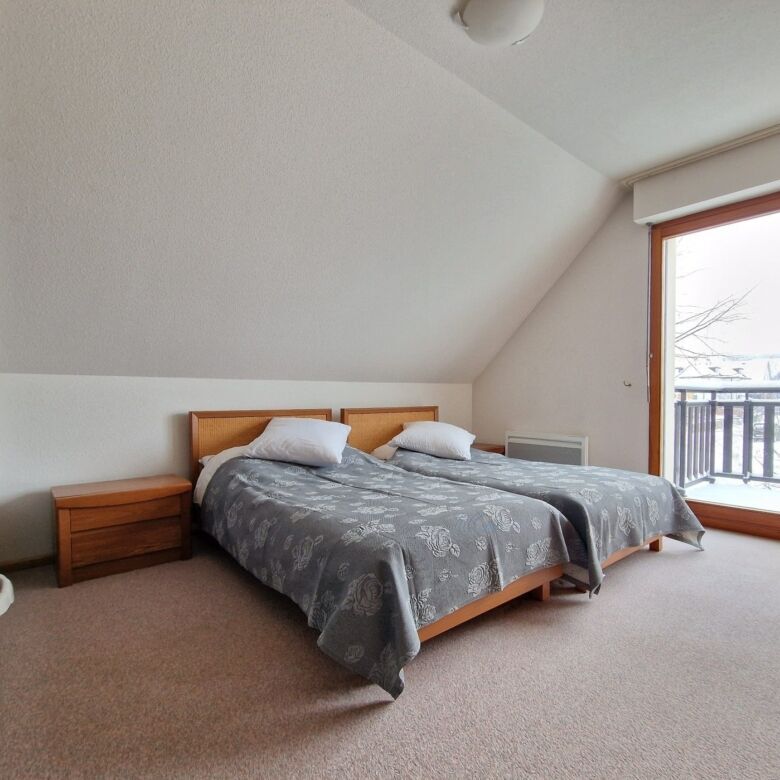 Comfortable bedroom with large balcony overlooking scenic surroundings.