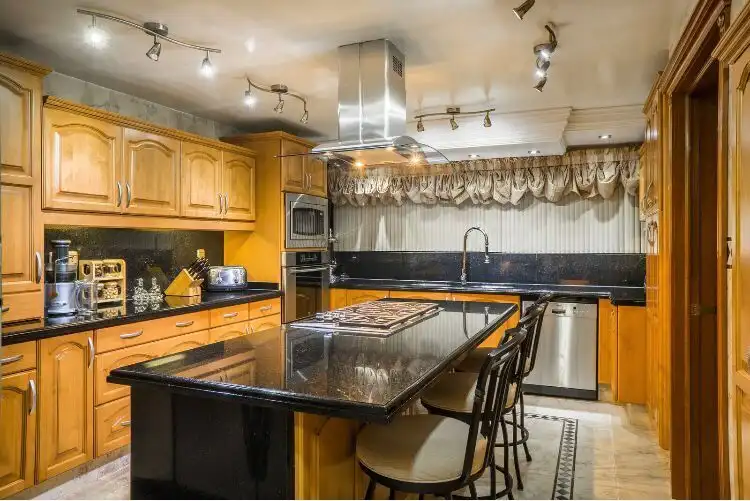 Spacious kitchen with wooden cabinets, black countertops, and modern appliances in a luxury Mexico C.