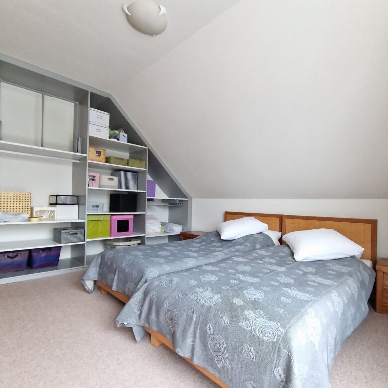 Spacious bedroom with a large bed and built-in shelving unit in Seppois-le-Bas. Ideal for comfortabl.