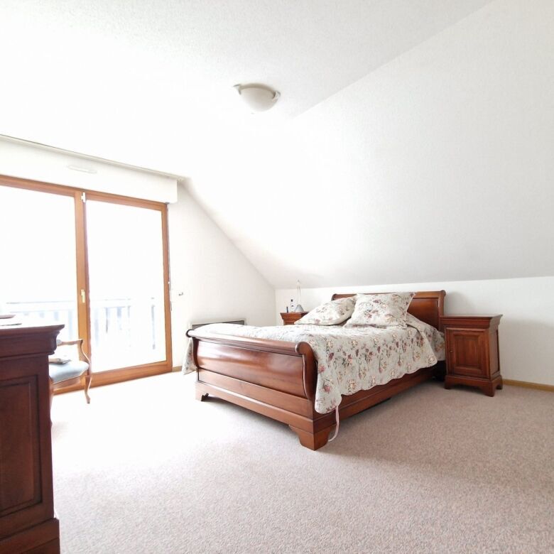 Bright bedroom with wooden furniture and large balcony door in Seppois-le-bas.