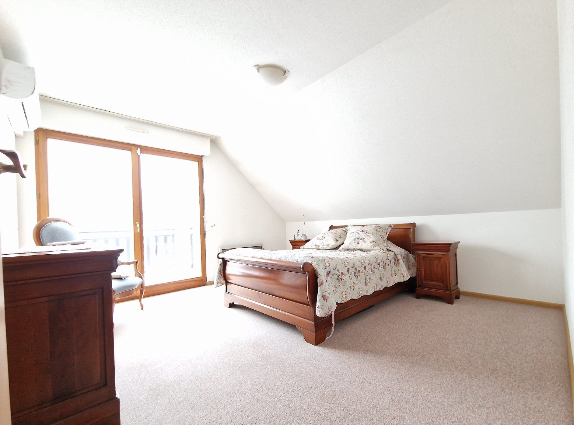 Bright bedroom with wooden furniture and large balcony door in Seppois-le-bas.