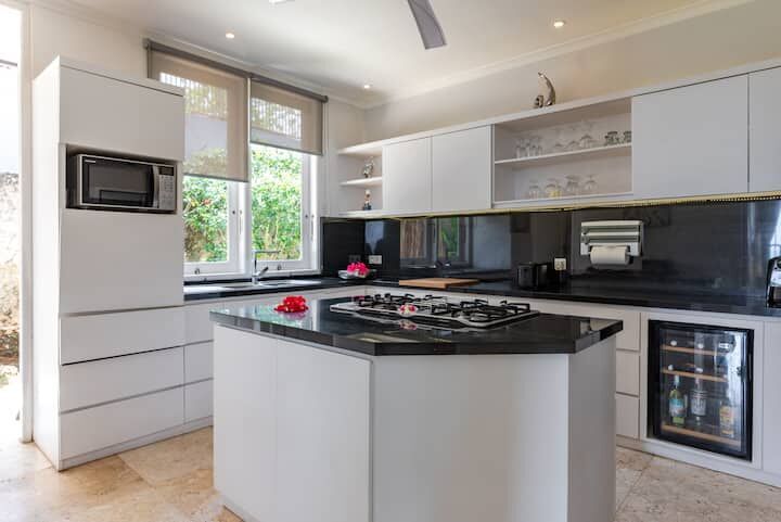 Modern Bali kitchen with white cabinets and black countertops.
