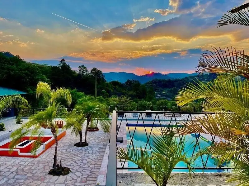 Style villa with pool overlooking lush mountains at sunset.