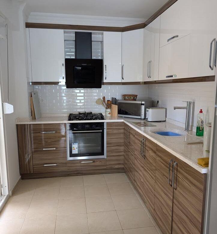 Modern kitchen with white and wood cabinetry, built-in oven, and appliances in Pearl Rock Retreat, A.
