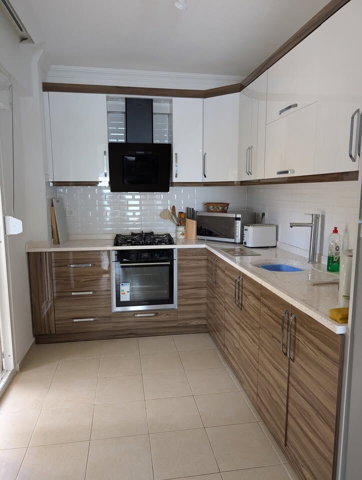Modern kitchen with white and wood cabinetry, built-in oven, and appliances in Pearl Rock Retreat, A.