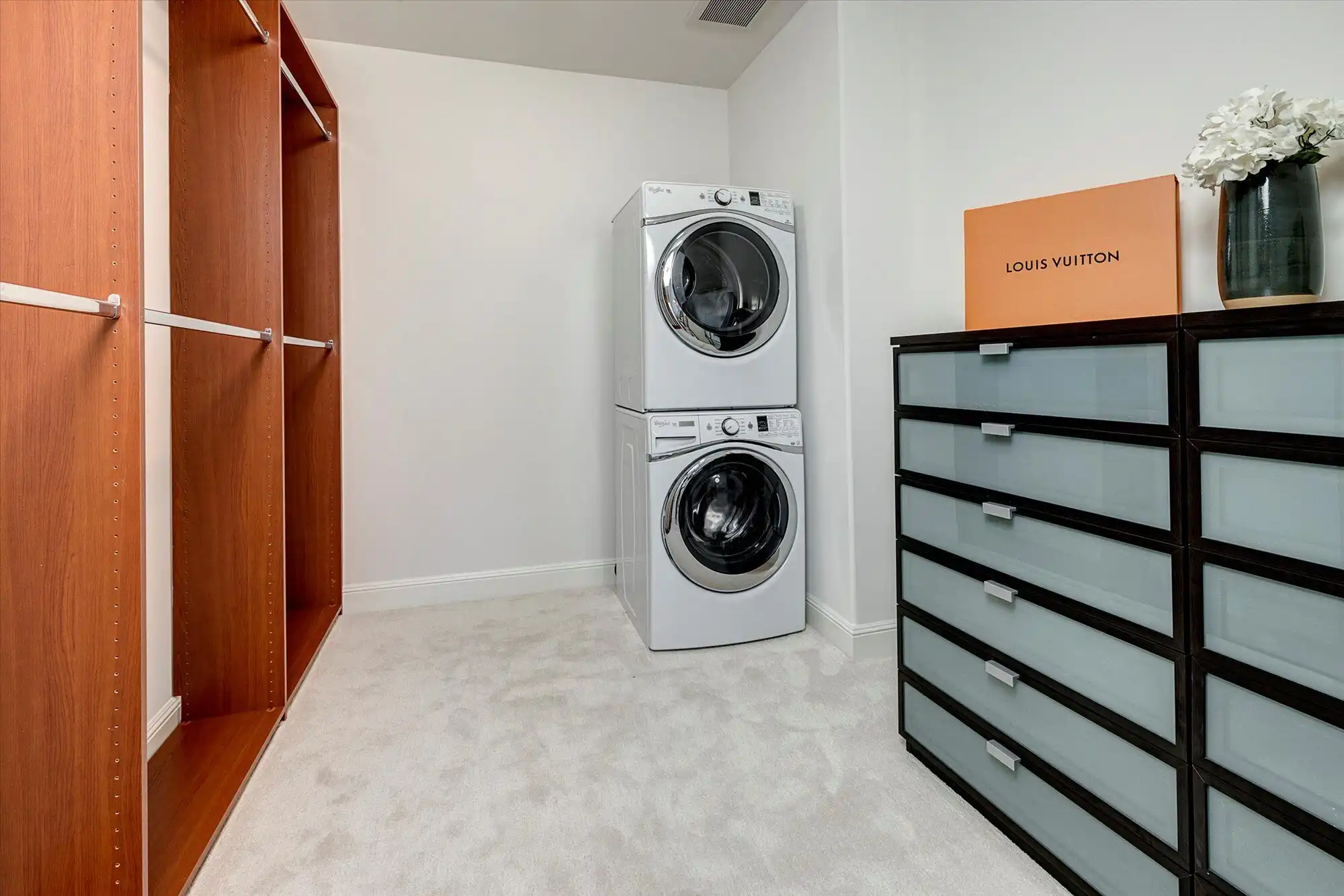 Laundry room featuring a stacked washer and dryer with ample storage and modern decor.