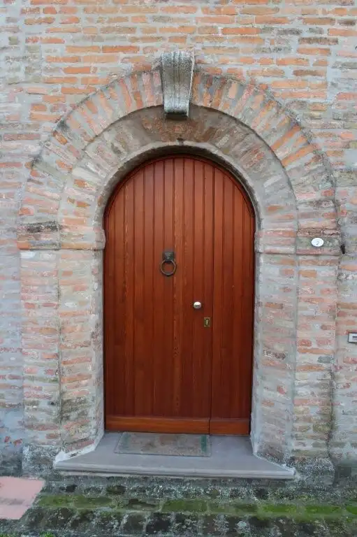 Door to a historic castle in Coriano Rimini, Italy, showcasing traditional brickwork and an arched s.